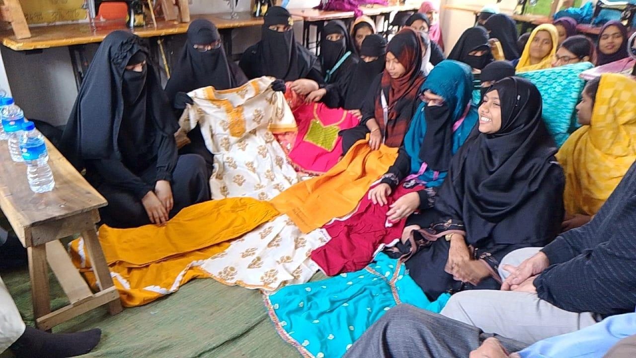 Women reviewing garments produced in a HAKF tailoring program